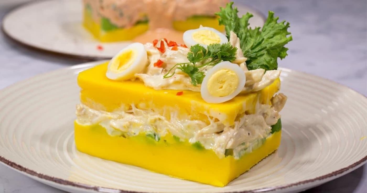 Plated Peruvian causa limeña layered with chicken salad, egg, and parsley