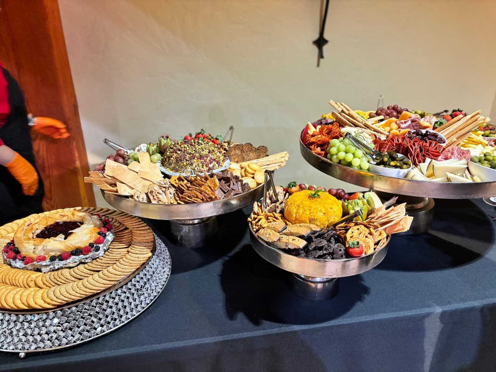 Tiered charcuterie and grazing display with cheeses, crackers, fruit, and cured meats