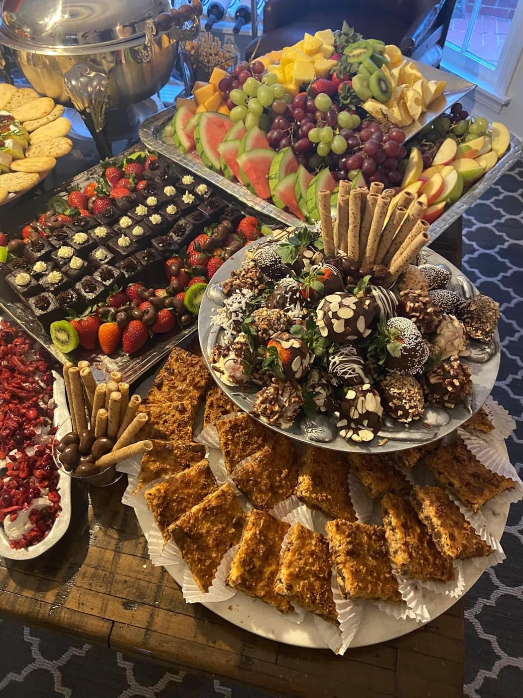 Dessert table with chocolate-covered strawberries, brownies, and a fruit platter