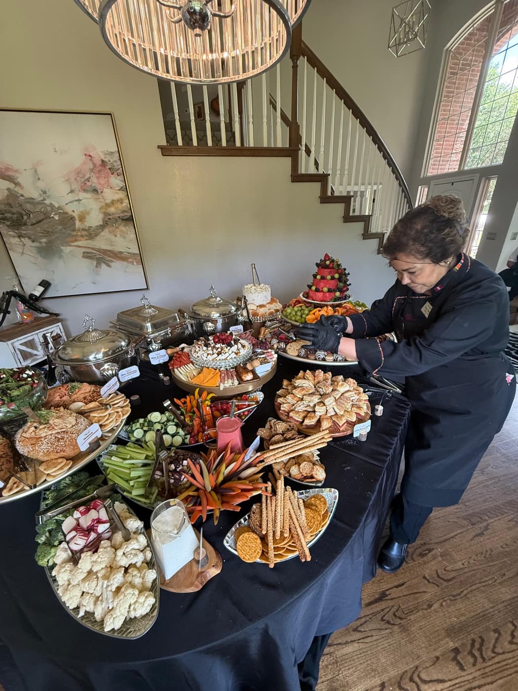 A catering team member styling a large grazing table in an event home